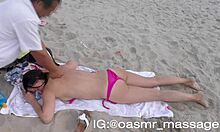 युवा प्रेमिका समुद्र तट पर टॉपलेस मसाज देती है।